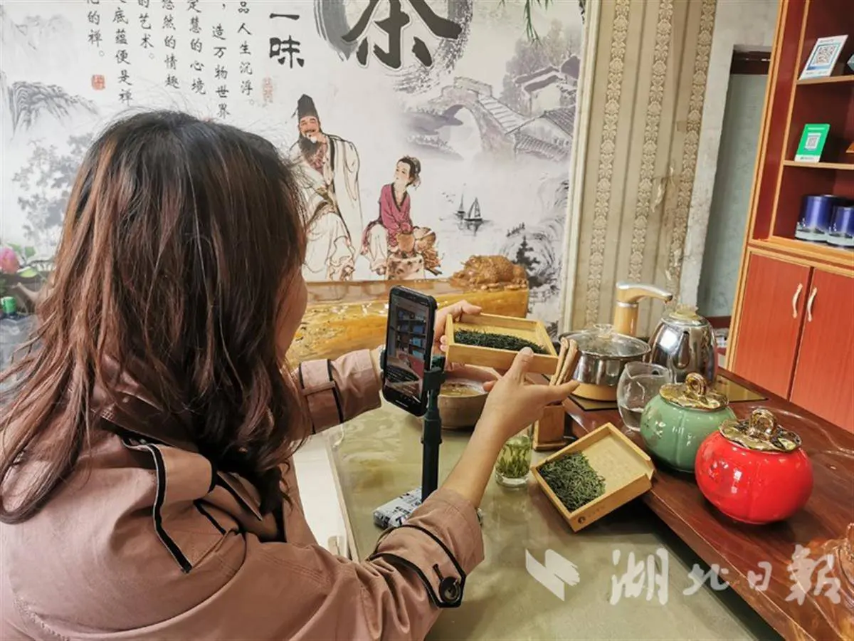 A tea seller showing loose tea to viewers through a smartphone livestream