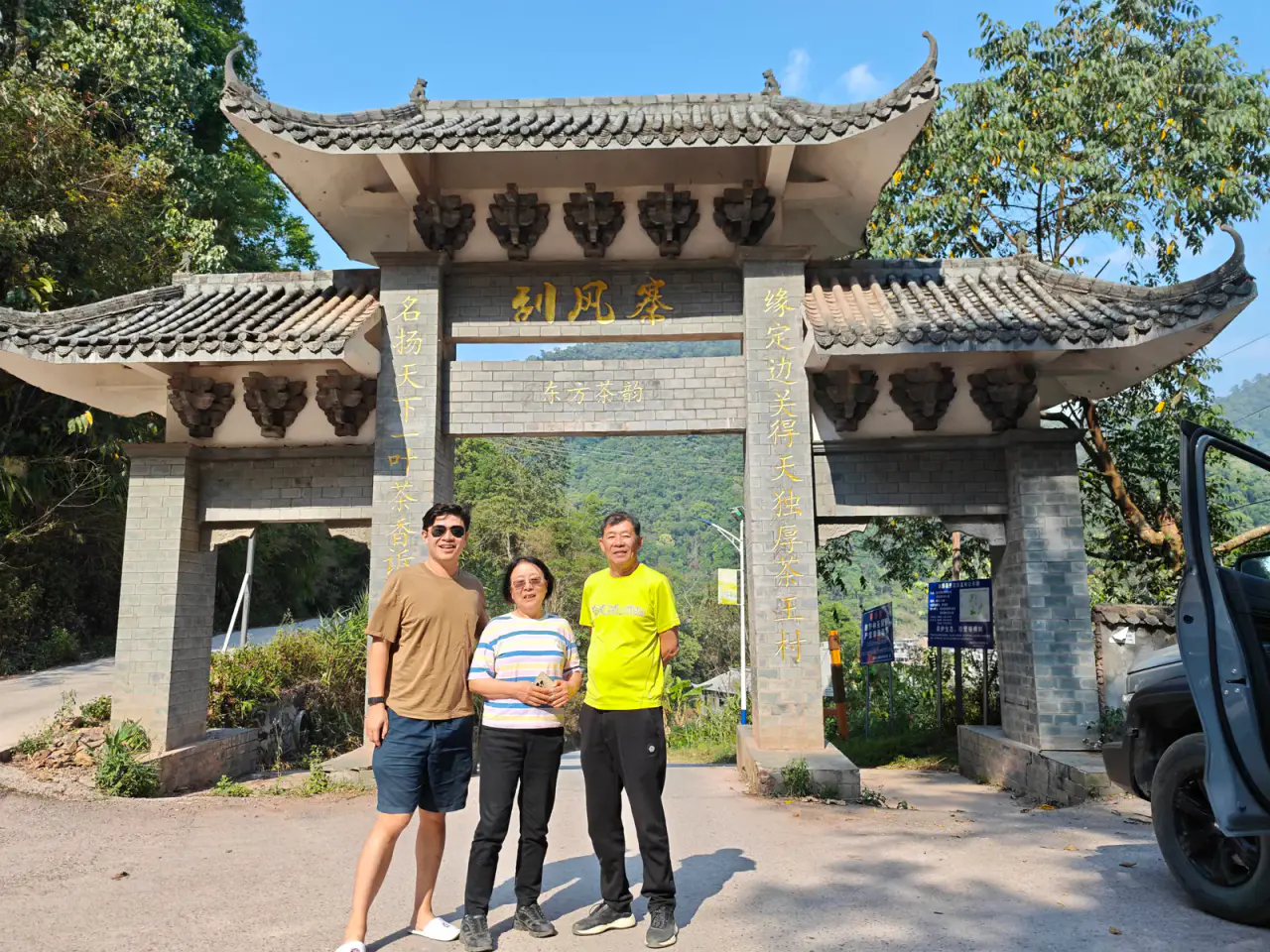 Three travellers standing at the stone entrance gate to Guafengzhai village